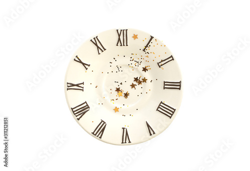 Small plate with tinsel and decorating golden stars inside. A saucer with clock face icon. White isolated.