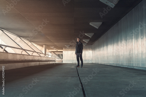 young man in black dress standing in a passageway covered in metal