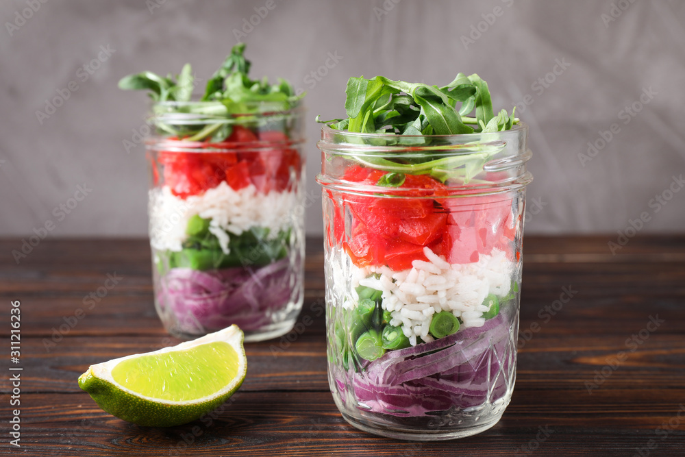 Healthy salad in glass jars on wooden table