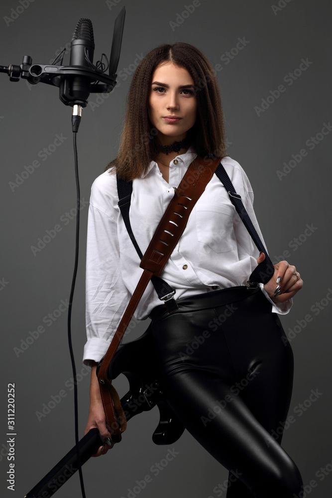 Girl musician with electric guitar and Studio microphone