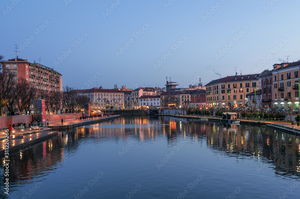 The dock (Darsena) in the tourist Navigli district while the first lights come on at sunset.Milan - Italy