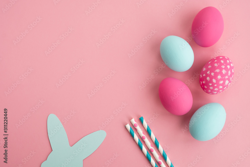 Colorful easter eggs and bunny rabbit ears made of paper on light pink background. Minimal composition in pastel colors. Top view, flat lay, copy space 