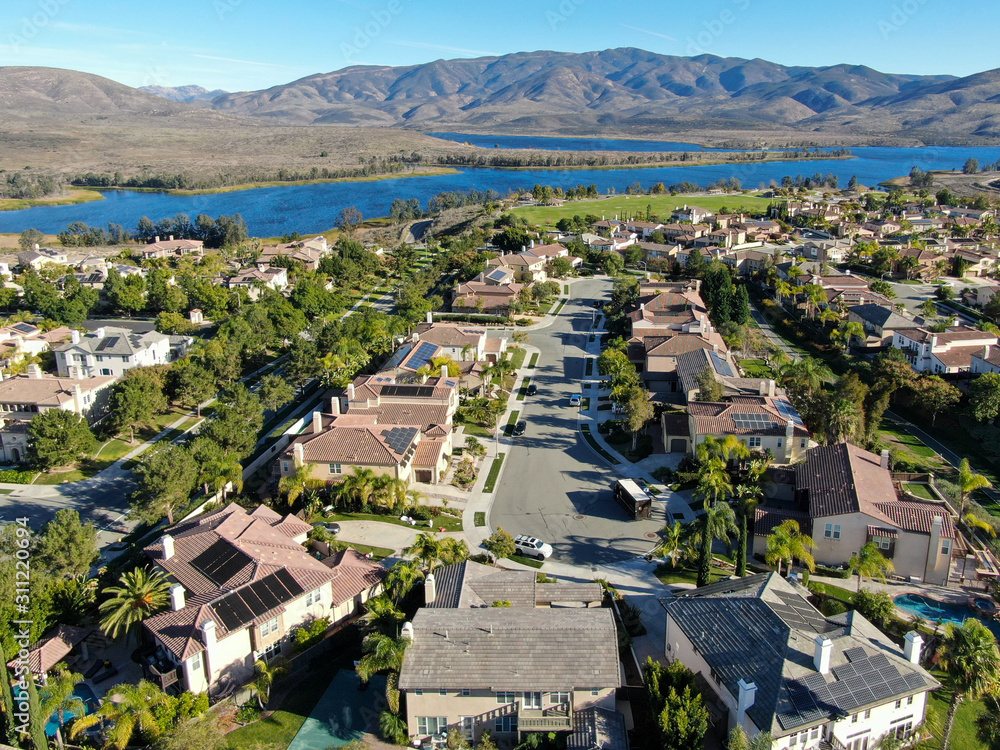 Aerial view of identical residential subdivision house with big lake and mountain on the background during sunny day in Chula Vista, California, USA.