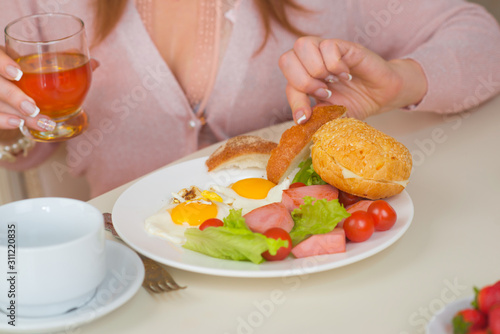 Girl eats scrambled eggs with tomatoes and sausage