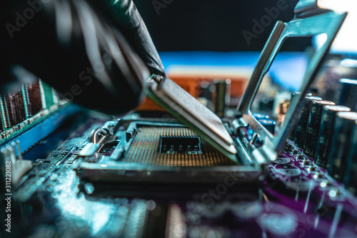 Engineer holding hands CPU to insert into the socket of the motherboard. Technology hardware and repair in neon light