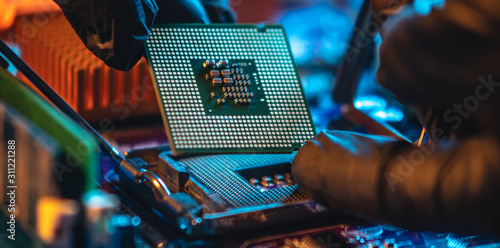 Repairman holding hands CPU to insert into the socket of the motherboard. Technology hardware and repair in neon light