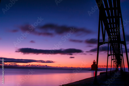 silhouette of lighthouse and pier at sunrise