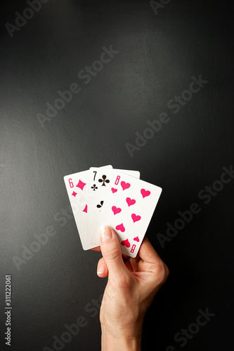 Cards in a hand on a black background. Three Card Poker. Rules and combinations of the game. Straight