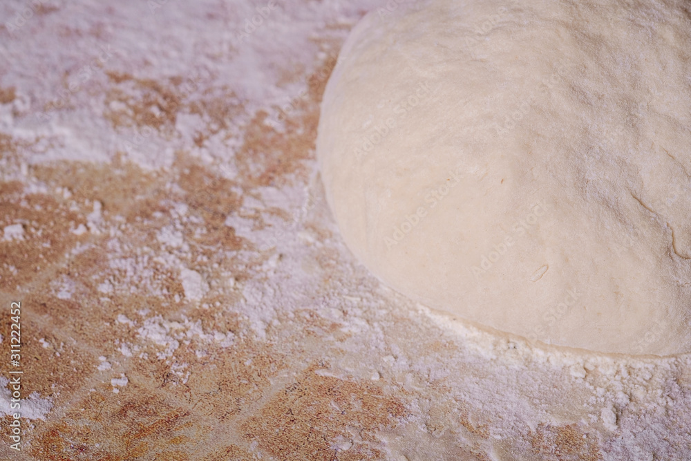 Prepared dough for baking pizza or bread on kitchen table with flour Prepared dough for baking pizza or bread on kitchen table with flour