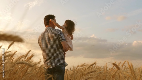 little daughter on fathers shoulders. happy child and father are playing in field of ripening wheat. baby boy and dad travel on field. kid and parent play in nature. happy family and childhood concept