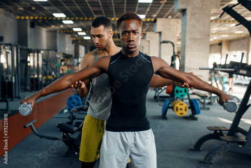 Two athletic men doing exercise with dumbbells