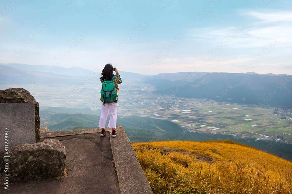 Young asian woman taking a photo on top of a mountain with beautiful view Young asian woman taking a photo on top of a mountain with beautiful view
