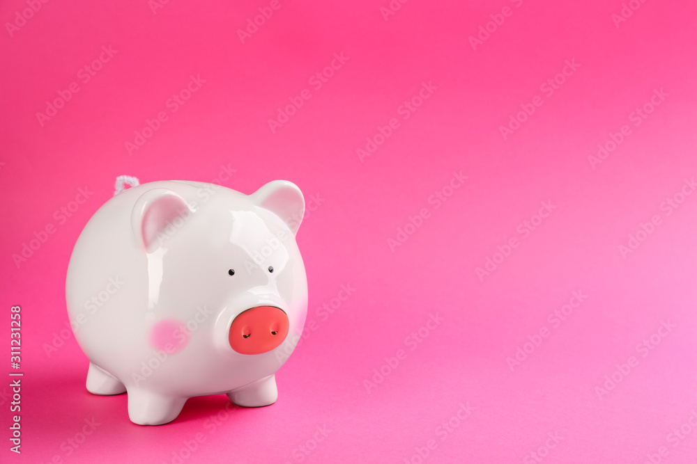 White piggy bank on pink background. Space for text