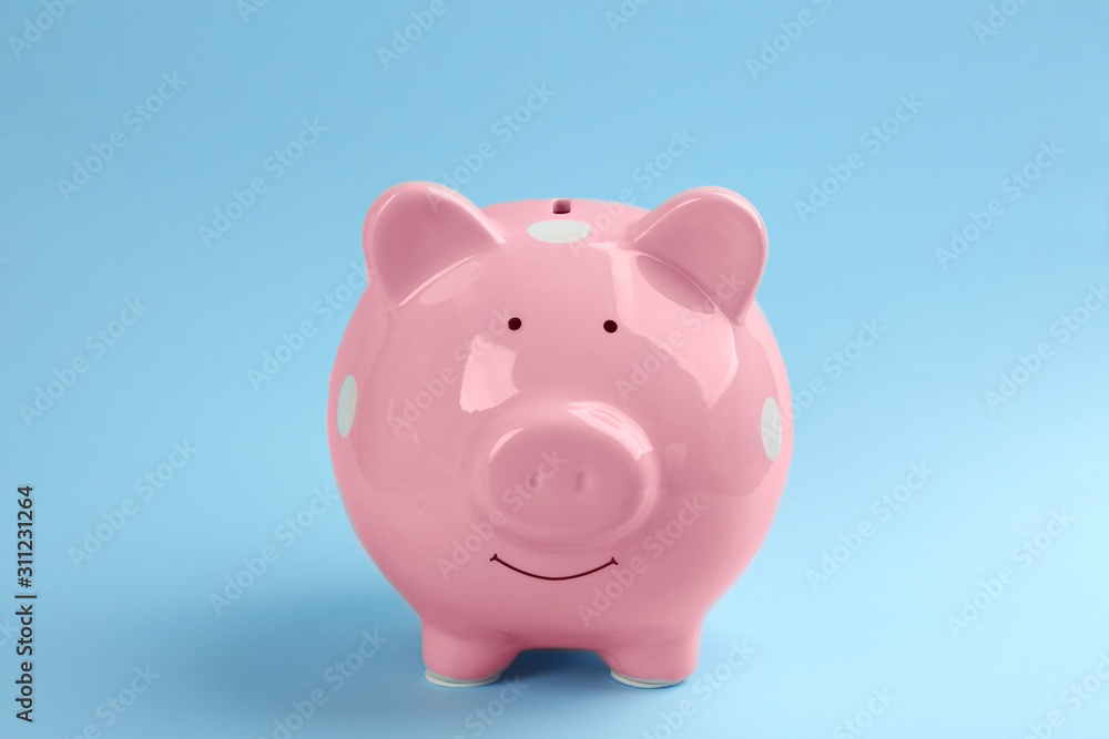 Cute pink piggy bank on light blue background