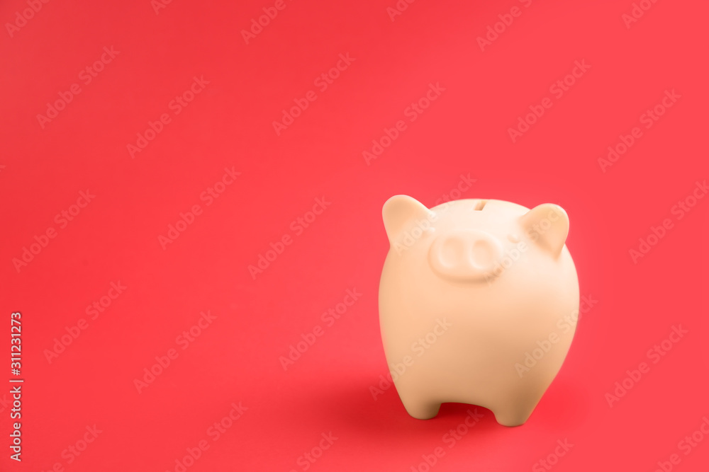 Beige piggy bank on red background. Space for text