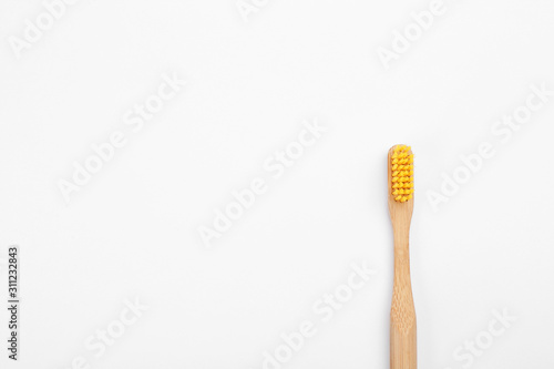 Bamboo toothbrush with yellow bristle isolated on white, top view