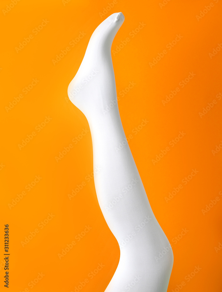 Leg mannequin in white tights on orange background Leg mannequin in white tights on orange background