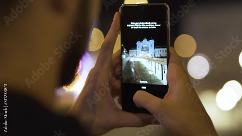 Close up of man using photo to take photo of Keleti Train station in Budapest at night photo