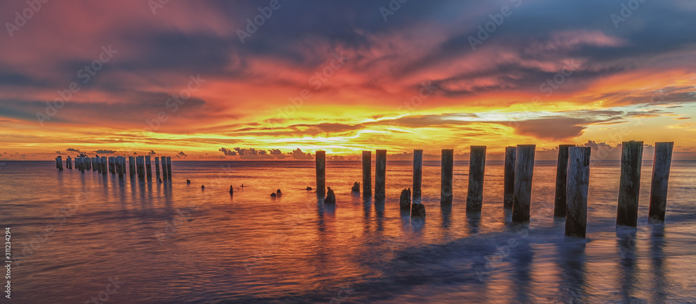 Old Pier at sunset. Scenery at the beach. Travel concept