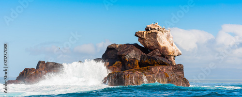 Rock in the ocean on a background of the cloudy sky, Galapagos Island, Isla Isabela. photo