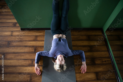 Young woman in yoga relaxing pose with legs up against wall, view from above