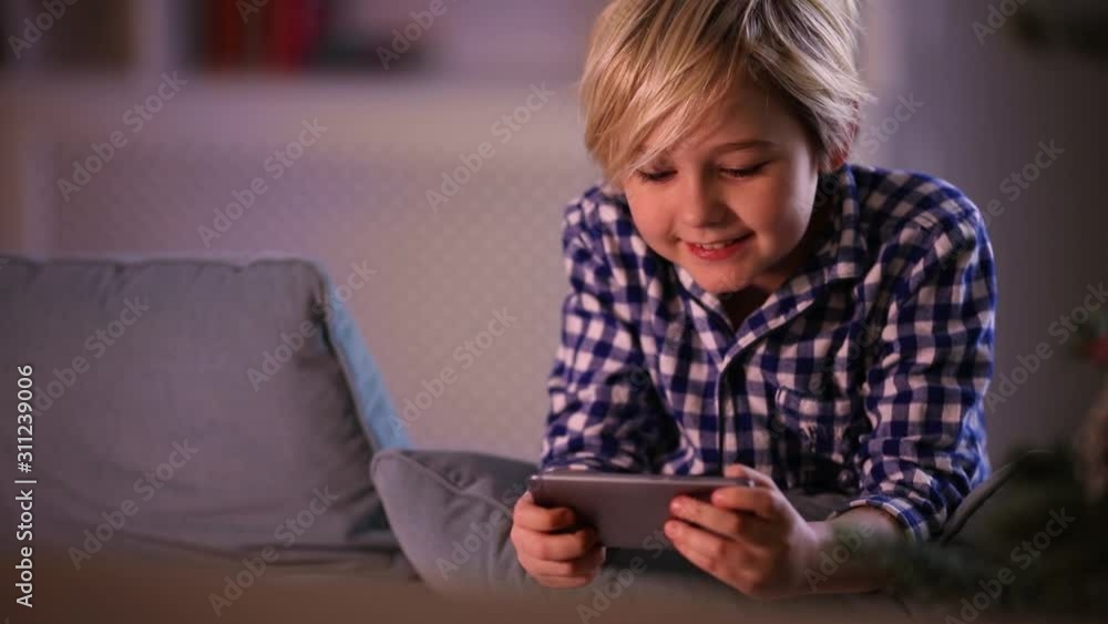 cute young boy, kid playing games on smart phone at home cute young boy, kid playing games on smart phone at home