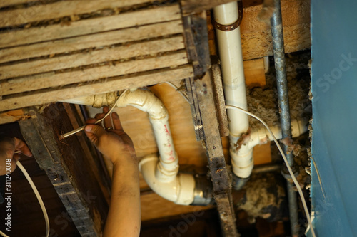 An electrician pulling wire through a hole in the ceiling.