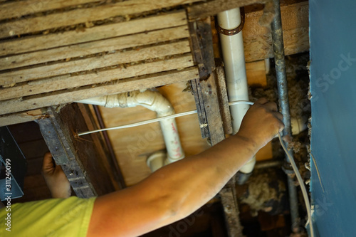 An electrician pulling wire through a hole in the ceiling.