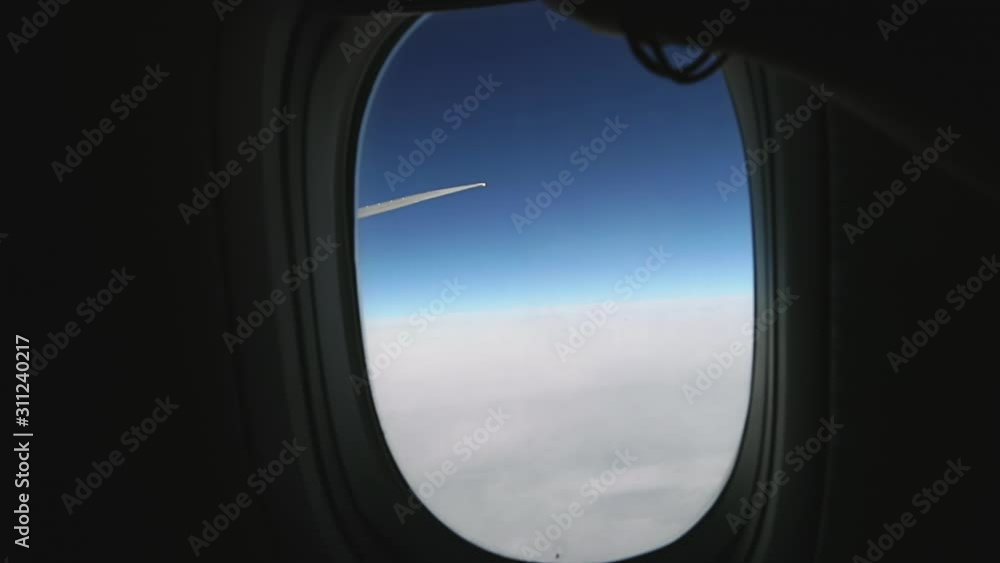 Hand closes an airplane window to relax during air travel. Passenger pov through plane window during flight. Close up of porthole of flying airplane. Aircraft above clouds. Air travel concept. Hand closes an airplane window to relax during air travel. Passenger pov through plane window during flight. Close up of porthole of flying airplane. Aircraft above clouds. Air travel concept.