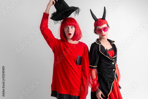 Two sexy girls dressed in halloween costumes posing in studio over white background.