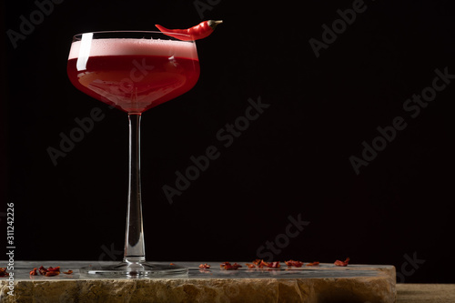 Red cocktail with foam, black background.