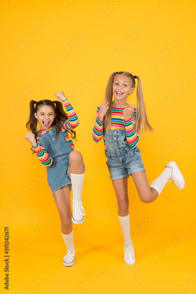 Obraz premium free and energetic beauty. happy childhood. real friendship. best friends forever. small sisters have fun. little girls jump yellow background. sense of freedom. finally summer vacation
