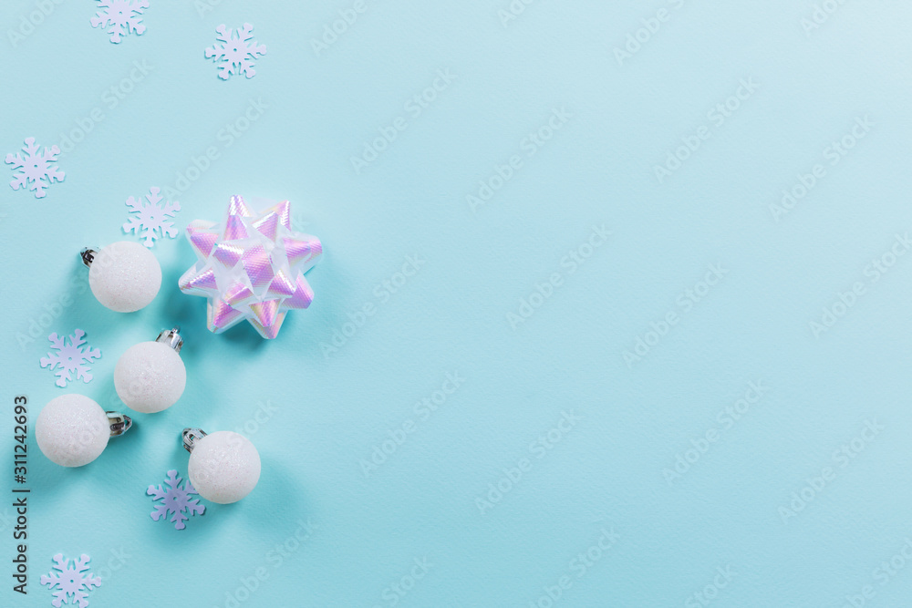 Blue background with white Christmas decorations and holographic bow. Holiday concept. Flat lay, copy space Blue background with white Christmas decorations and holographic bow. Holiday concept. Flat lay, copy space