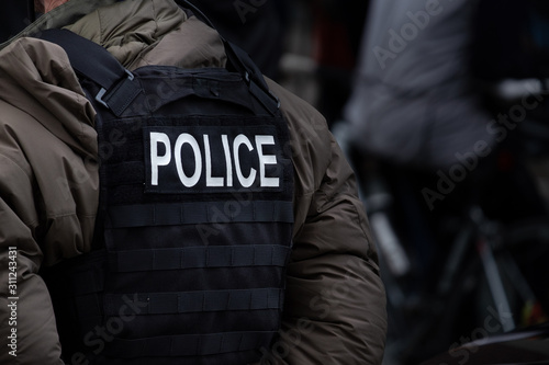 Billede på lærred A male police officer dressed in winter clothes stands back on to the camera