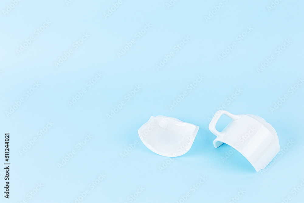 broken white cup on blue background broken white cup on blue background