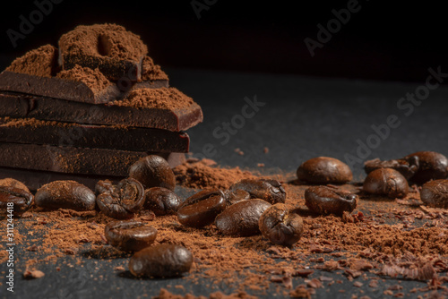 Coffee beans with broken chocolate slices close-up on a dark background