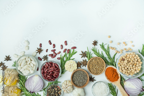 Fototapeta Naklejka Na Ścianę i Meble -  Cooking background, herbs, salt, spices, olive oil, white background copy space. View from above. Healthy food concept with fresh vegetables and cooking ingredients. Table background menu.