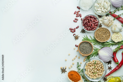 Cooking background, herbs, salt, spices, olive oil, white background copy space. View from above. Healthy food concept with fresh vegetables and cooking ingredients. Table background menu.