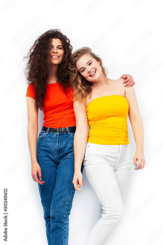 young pretty teenage girls friends with blond and brunette curly hairs posing cheerful isolated on white background, lifestyle people concept young pretty teenage girls friends with blond and brunette curly hairs posing cheerful isolated on white background, lifestyle people concept