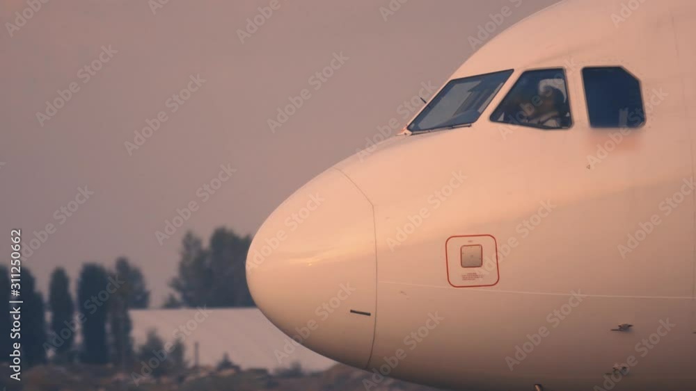 A close-up shot of the cockpit of an airplane that is taxiing on the taxiway after landing at sunset A close-up shot of the cockpit of an airplane that is taxiing on the taxiway after landing at sunset