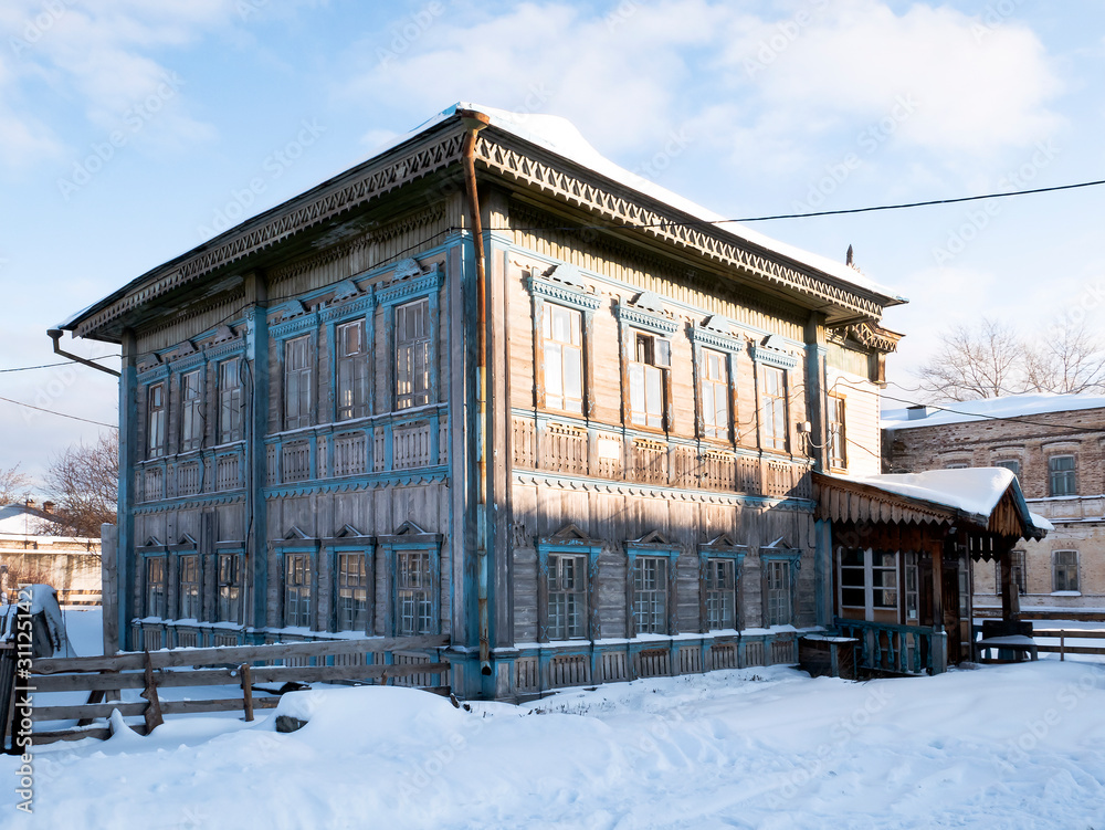 Russian old wooden two-storey house of pre-revolutionary construction, Sunny winter day.