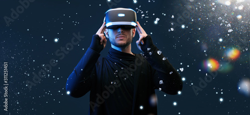 Young man on virtual reality background. Guy using VR helmet. Augmented reality, future technology, game concept.