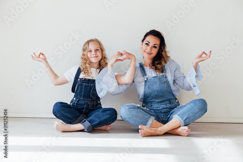 Mom with little girl in denim jumpsuit play in white room