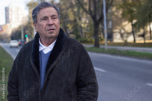 Portrait of a pensive senior man in the street, outdoors, traffic. Old man relaxing outdoors and looking away. Portrait of senior man looking thoughtful