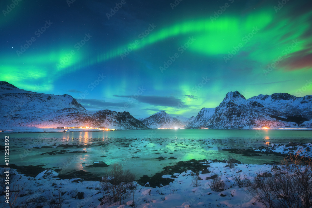 Photo sur Plexiglas Aurore boréale sur la côte, montagnes enneigées et  lumières de la ville la nuit. Aurores boréales dans les îles Lofoten,  Norvège. Ciel étoilé avec aurores polaires. Paysage d&#39;hiver avec
