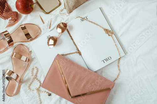Pink styled women fashion composition with female accessories, bijouterie, accessories on white linen in bed. Flat lay, top view template for social media, website, magazine. photo