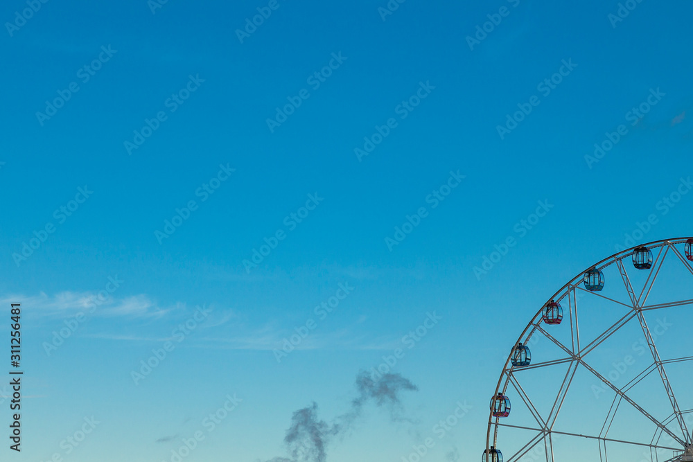 The background image is clear blue sky. In the lower right corner is a fragment of the Ferris wheel.