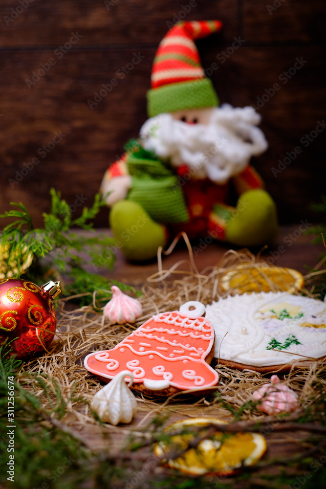 Wooden background with decorative gingerbread snowman cakes, Christmas tree branches and Santa. Christmas postcard with sweets food, dessert.