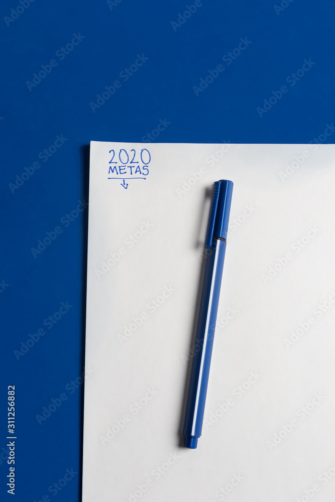 Stockfoto Lapicero negro con azul sobre escritorio azul clásico con hoja de  papel listo para las metas 2020 en español escrito con tinta azul