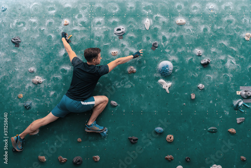 A man climbing in boulder gym in the wall.